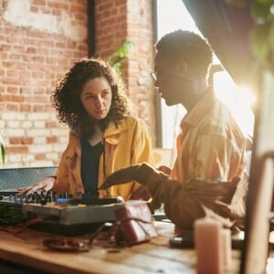 Young woman looking at black man explaining her how to create new music