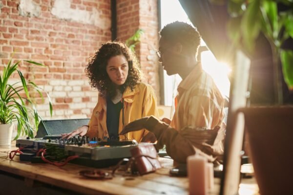 Young woman looking at black man explaining her how to create new music